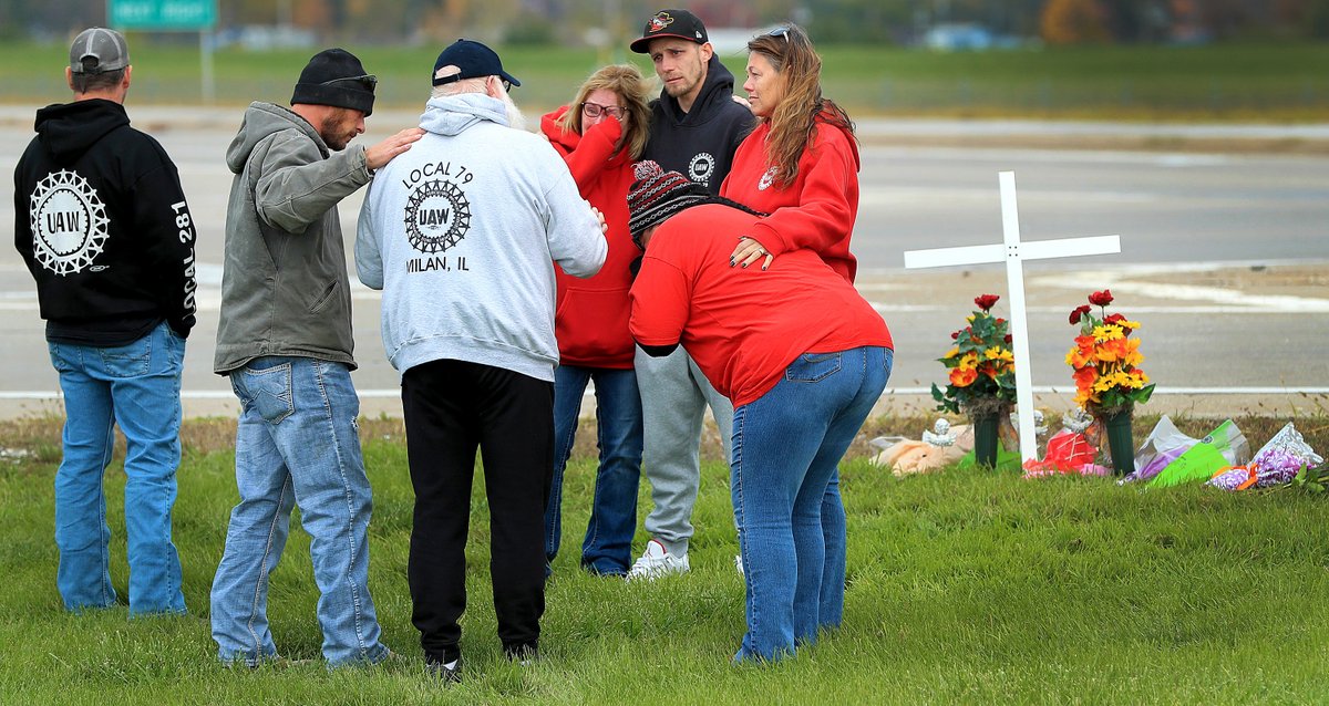 Striking employees with the John Deere Distribution Center in Milan, Ill &amp; members of Local 79, hug console each other at a memorial site at the entrance to the plant where a fellow striker was struck and killed by a vehicle early Wednesday morning.(photo by John Schultz)