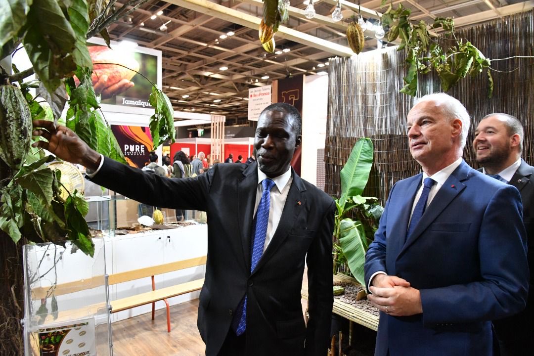 BandamanK's tweet photo. Salon du Chocolat à Paris, Stand de la CI avec M. Alain Griset, le Ministre français des PME. Comme dans un champ de cacao, j’explique à mon hôte le processus de la récolte au séchage de la fève avant l’étape sa transformation en chocolat. La CI en est à 40% aujourd’hui. https://t.co/rDCDm8behe