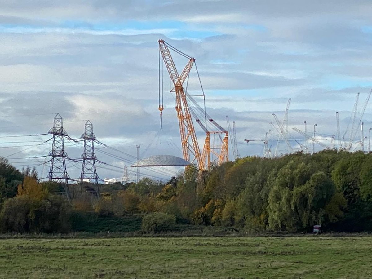 A horrible distant crooked iPhone picture of a #FlyingSaucer at #HinkleyC.  It came in very slowly to land next to another one.  Presumably the tops of reactor domes?