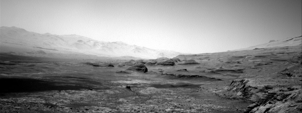 black and white photo of desert landscape with rock formations in the foregrounds and mountains in the background