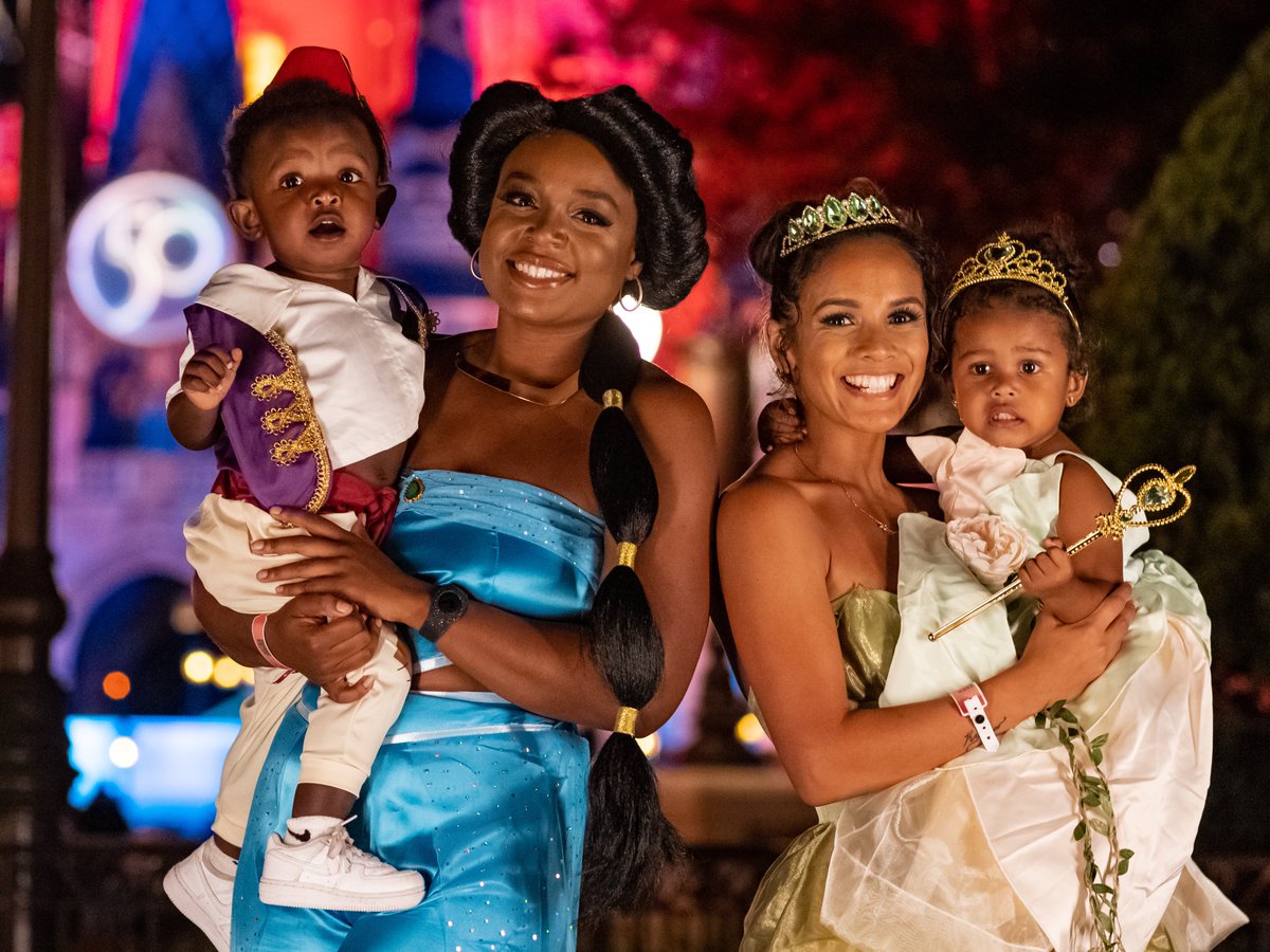 Family Halloween photo dressed as characters from Aladdin and The Princess and the Frog in front of Cinderella castle