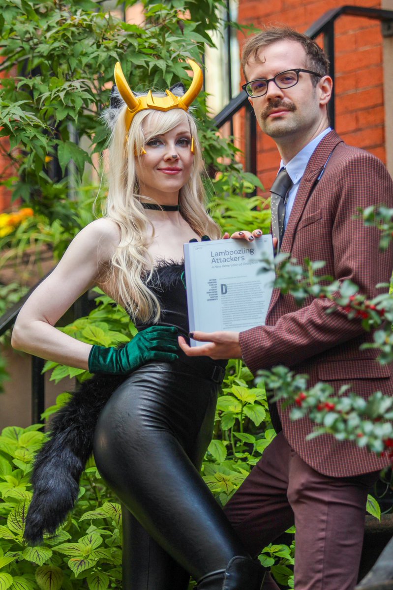 A picture of Ryan Petrich and Kelly Shortridge. Kelly is dressed in costume as a Loki-kitty variant, also known as “Lokitty”, and Ryan is dressed as Agent Mobius. They are holding a tablet that reads “Lamboozling Attackers: A New Generation of Deception”, a recent paper they published in ACM Queue.
