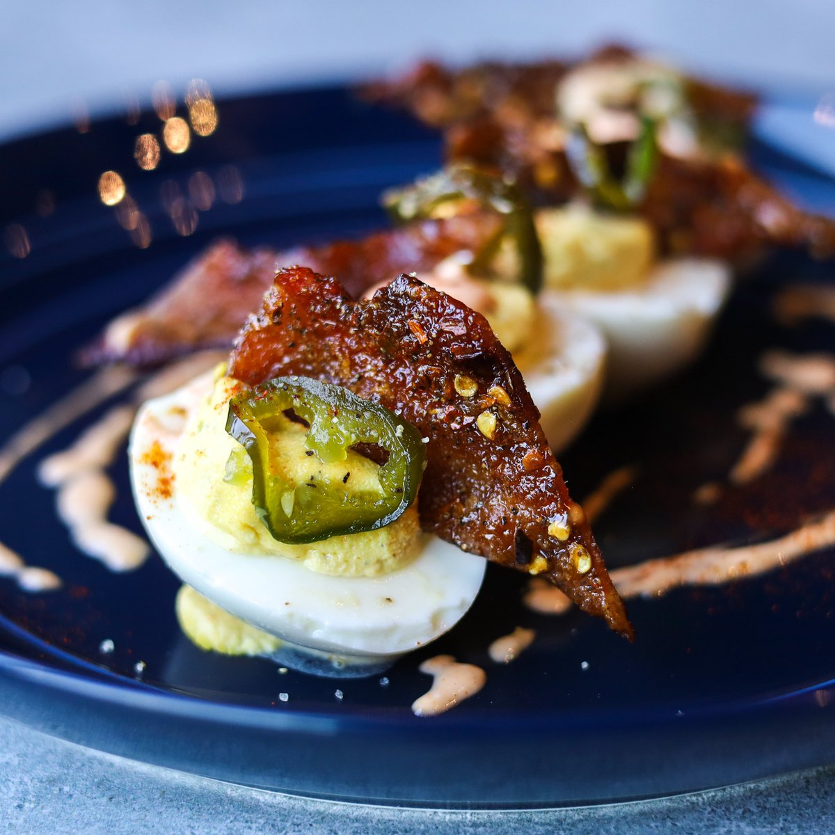 NEW! Deviled eggs with candied jalapeños, candied bacon and hot sauce mayo. Trust us, they're devilishly good 🔥 #NationalDeviledEggsDay