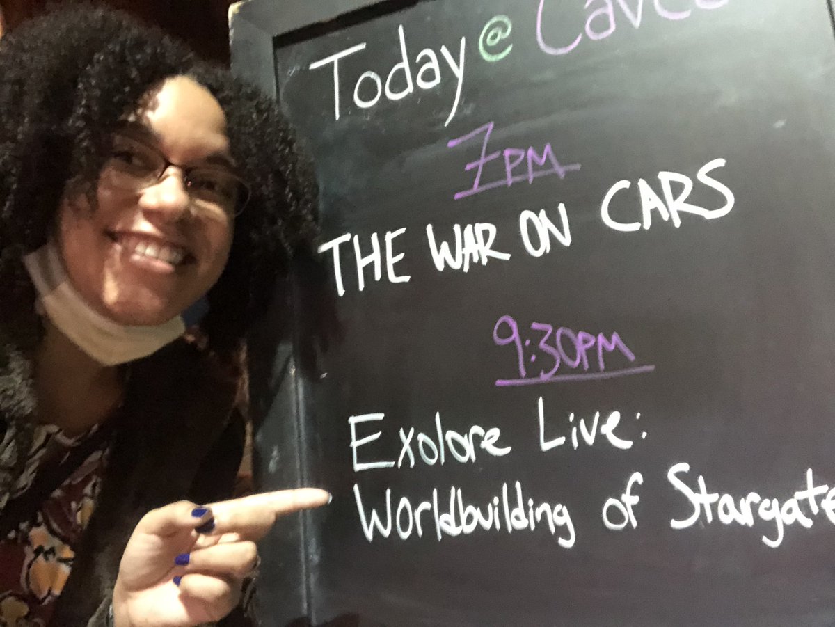 Selfi of me pointing at the chalk announcement board outside Caveat. The sign says 9:30pm Exolore Live: Worldbuilding of Stargate