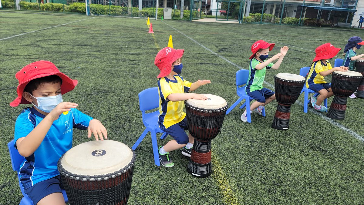 infants_TTS's tweet photo. The first official whole school House Day and SMMs aren't going to get in the way of team building! The Infants have been drumming their House rhymes with the music team on the astro and each class was very excited to get a visit from Griff the Lion, with all his house badges! https://t.co/4ugLCLI7qO