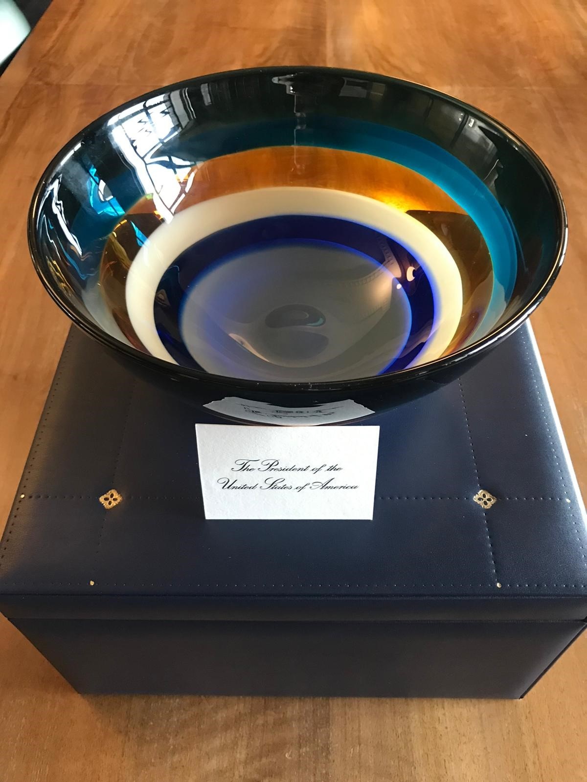 A multi-coloured vase gifted to the people of Scotland from President Biden with an accompanying card reading The President of the United States of America