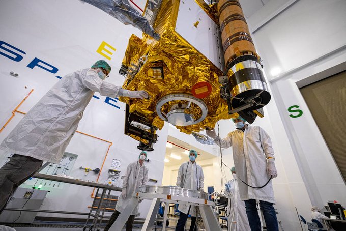 engineers in clean room gear work on a refrigerator-sized spacecraft