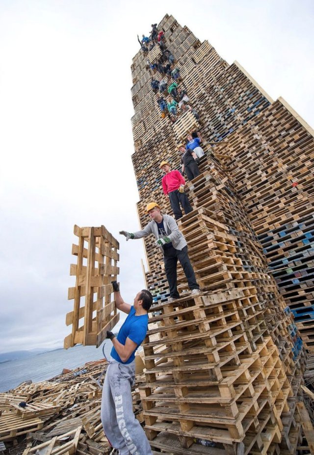 The construction of Poynton Bonfire from railway sleepers for George VI coronation, compared to the people in Alesund, Norway stacking pallets. #BonfireNight #bonfirenight2021 #construction #building #uk #5thofNovember