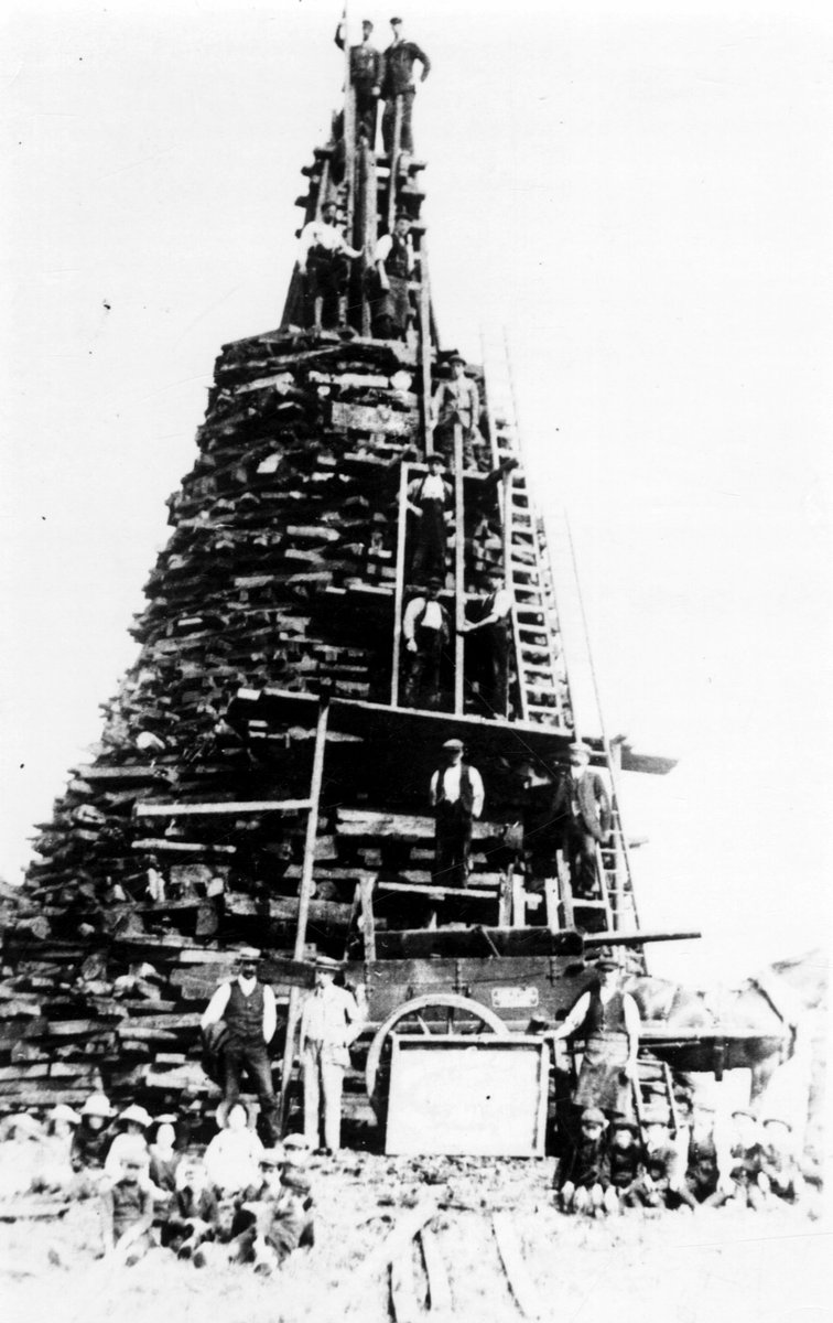 Construonetwork's tweet photo. The construction of Poynton Bonfire from railway sleepers for George VI coronation, compared to the people in Alesund, Norway stacking pallets. #BonfireNight #bonfirenight2021 #construction #building #uk #5thofNovember https://t.co/8uOX6ztfei