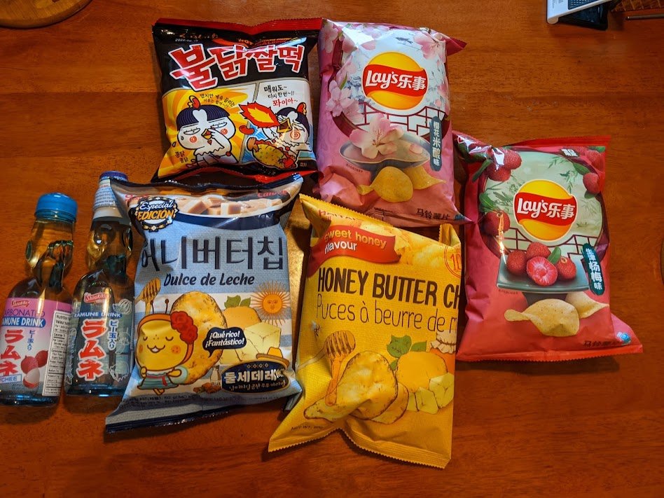 Various Korean and Japanese snacks like Tomato Lays, Spicy Ramen Chips, Honey Butter Crisps and Ramune.