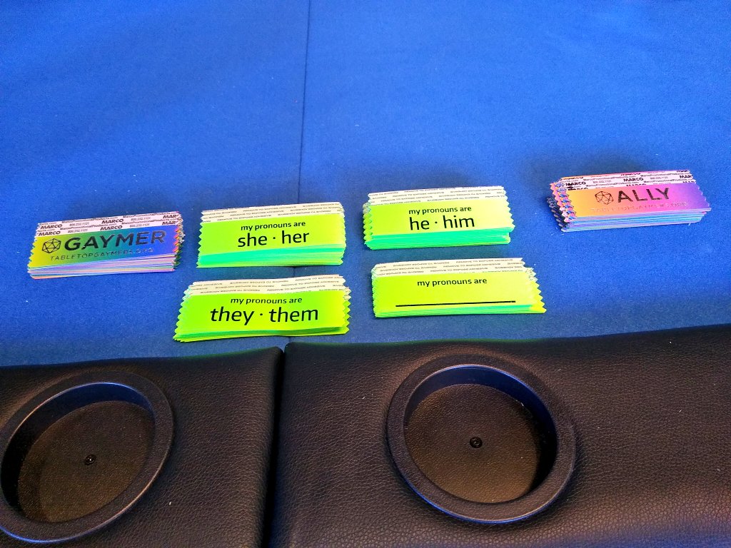 newaregames's tweet photo. Setting up for @CarnageCon, we will be passing out pronoun and Gaymer ribbons from @TabletopGaymers in the Carintha lodge.  Come to booth 1 on the second floor, open at noon today! https://t.co/igLBGpZuPd