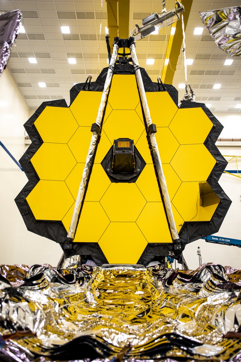 The James Webb Space Telescope with its primary mirror fully deployed. All 18 of its gold-coated hexagonal segments are shown, resembling a honeycomb.