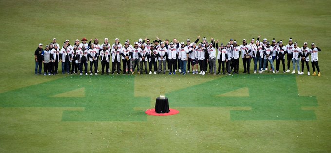 The entire 2021 Atlanta Braves surround the â€œ44â€ painted in centerfield along with the World Series trophy