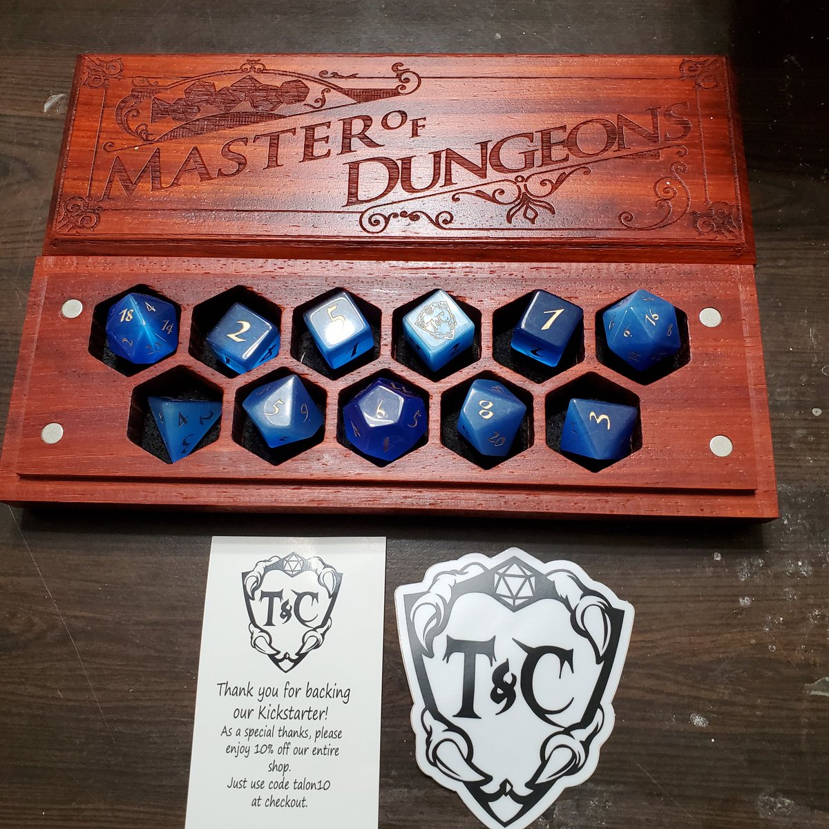 RossSimmerman's tweet photo. Received my Kickstarter package from @talonclaw today, stunning work from @88riddles Padauk dice vault and Blue Cat's Eye dice.
#talonandclaw #88riddles #dnd #gemstonedice #dice #TTRPGs #dicegoblin https://t.co/qlRWqVFBOE