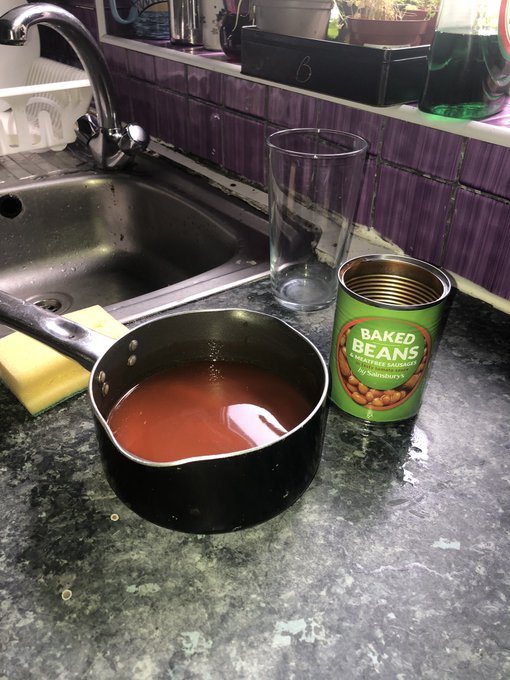 A saucepan filled with tomato juice from baked beans but no beans and a tin of baked beans next to it