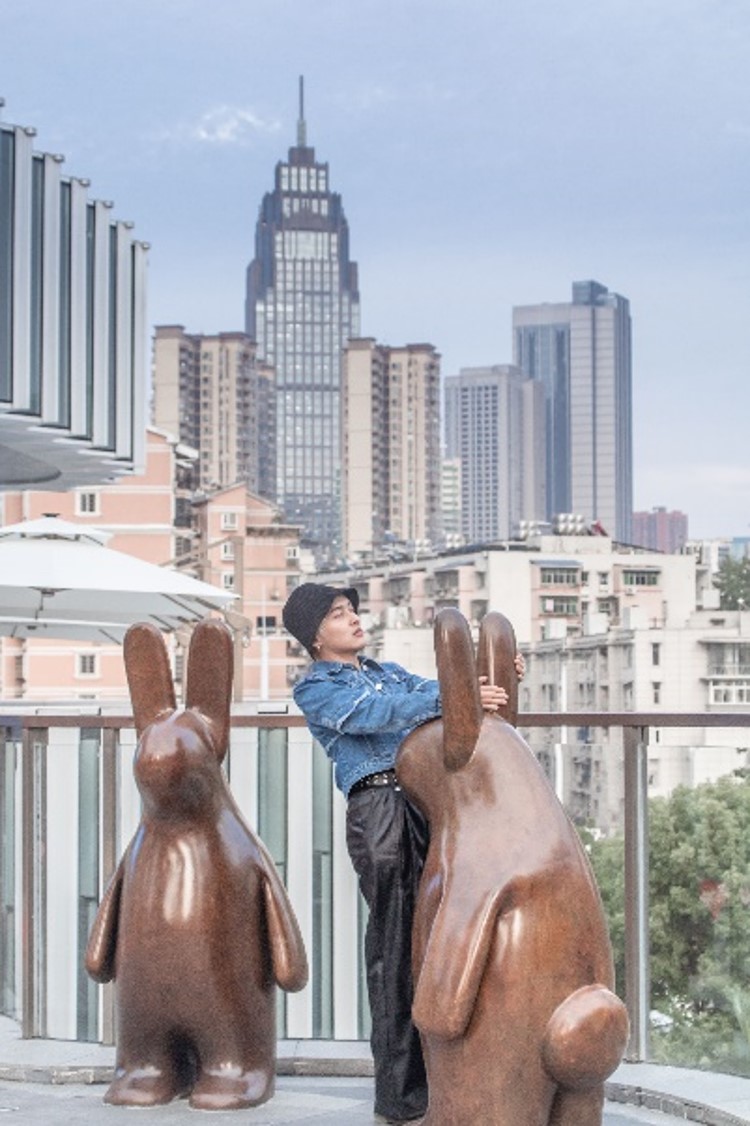 The brown sculpture in the shape of a rabbit, the contrasting fence of Huafa Zhongcheng Hui Commercial Street, the bright red and orange collide with a visual awe-inspiring. The fervent impact and the harmony of the blue jeans make the boy and the streetscape blend into one.