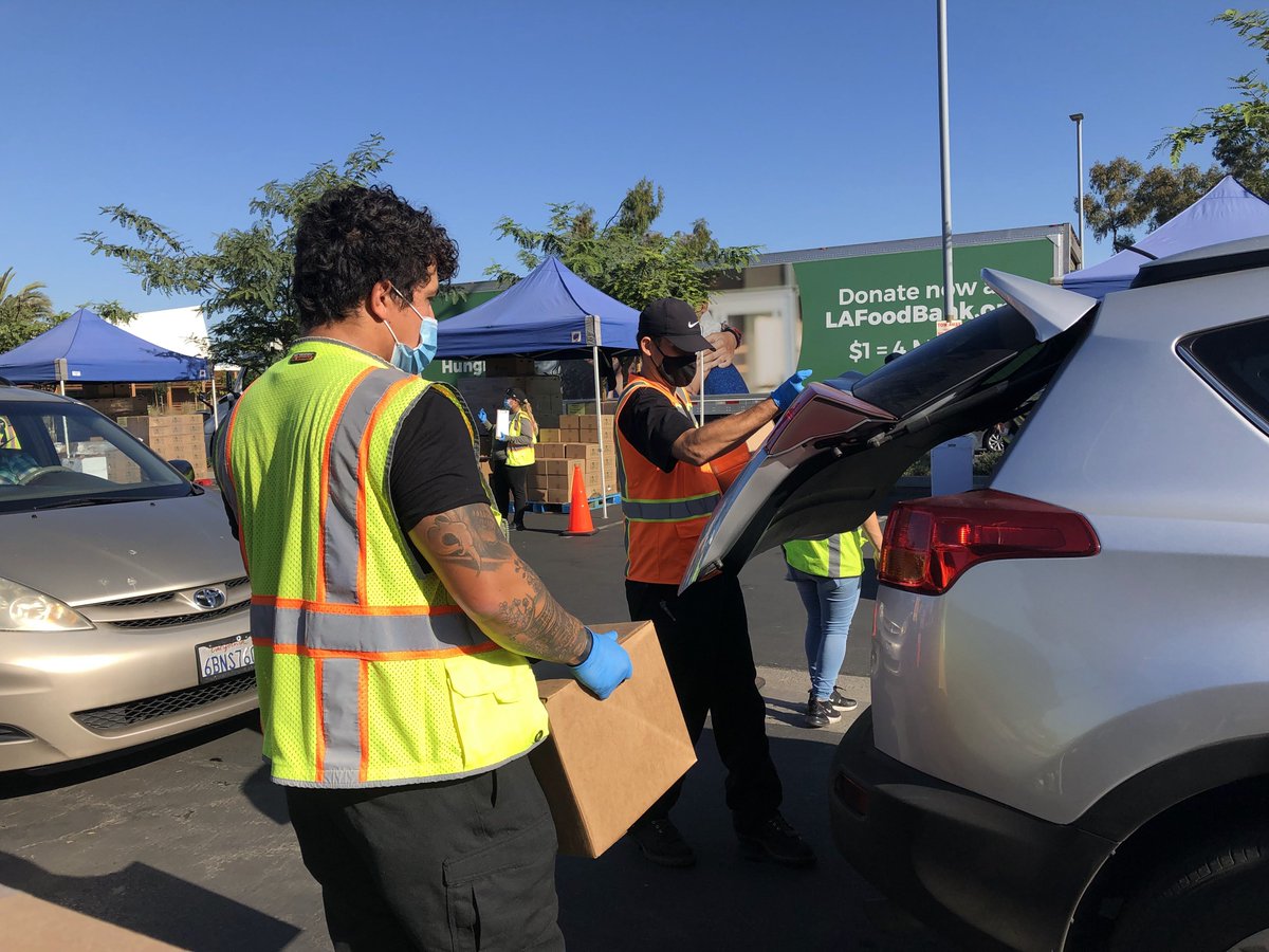 A LA Regional Food Bank volunteer loads a car with food resources at a drive-through food distribution.