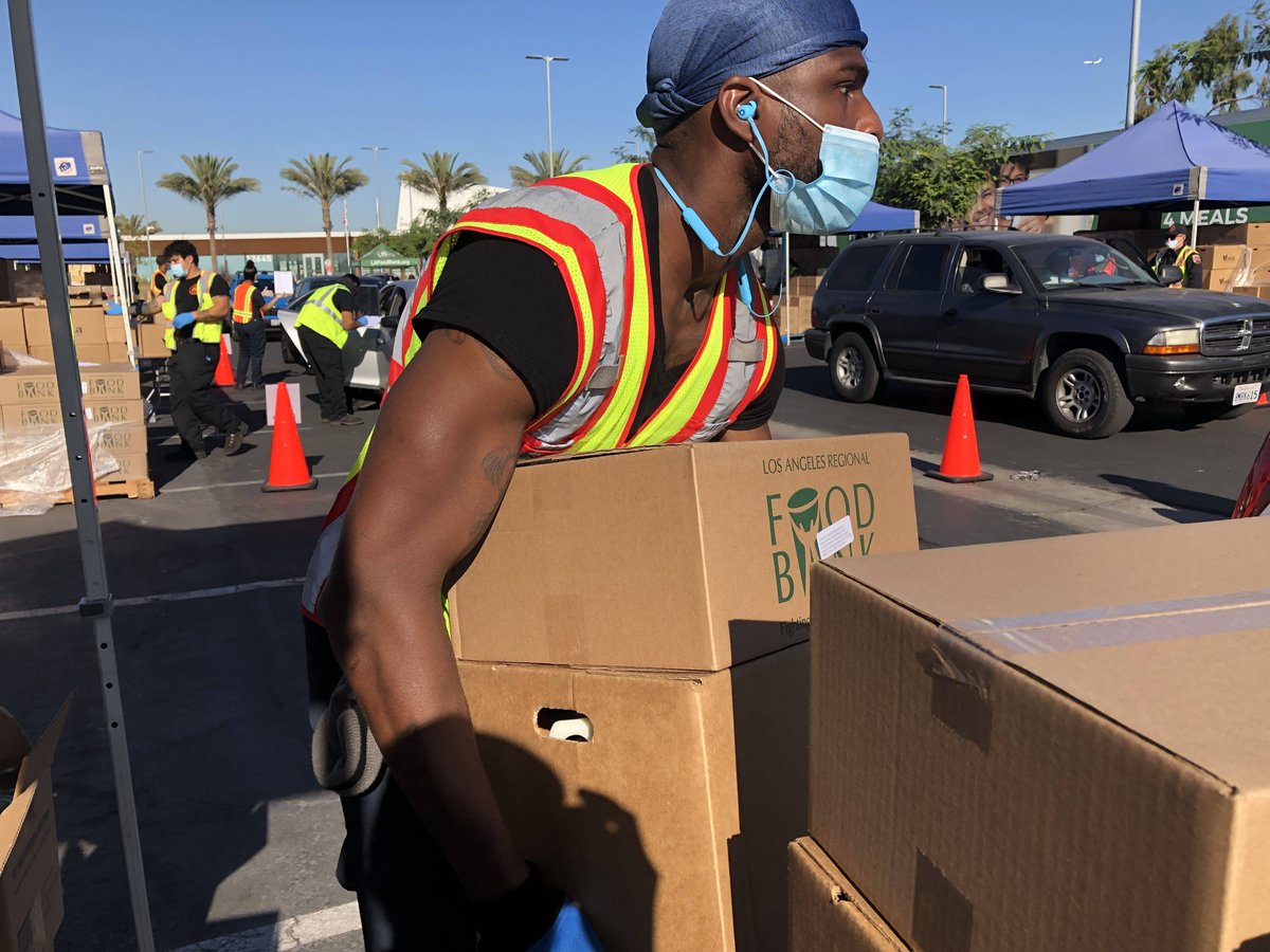 A LA Regional Food Bank volunteer loads a car with food resources at a drive-through food distribution.