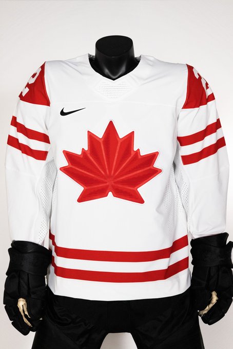 A Canadian hockey jersey on a headless mannequin. The jersey is white with a red maple leaf in the centre, two thick red stripes at the bottom and around the upper arm. The shoulders have a bit of red and the numbers on the red are white. 