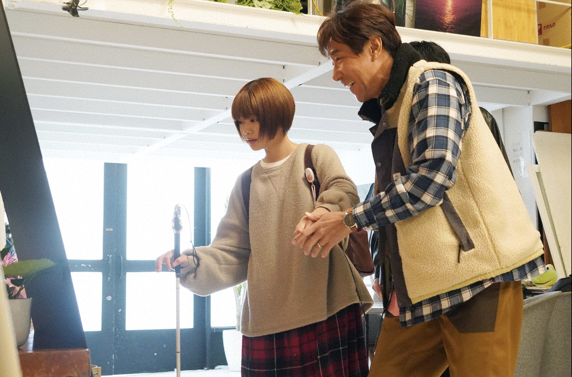7話の場面写真。場所は写真スタジオ。ユキコとセイジが立っている。笑顔のセイジがユキコの手をとりながら、二人は目の前にある何かを見ている。