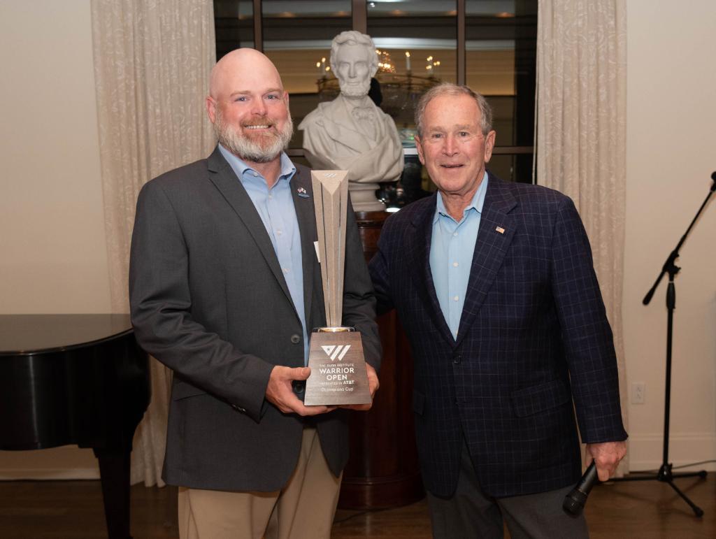 ATT's tweet photo. We're proud to support the #WarriorOpen @theBushCenter, a golf tournament that focuses on sports as a rehabilitation for wounded or injured post 9/11 service members.  Congrats to Captain Adam Napier on winning the Champion’s Cup! 🏌️ 🇺🇸 #VeteransDay https://t.co/OWwT95AZ8C