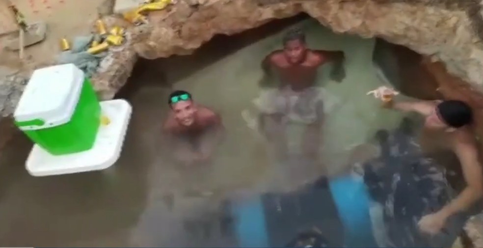 g1's tweet photo. Com isopor e cerveja, moradores tomam banho em buraco de obra em rua de Belém; veja vídeo https://t.co/QyYGCWXbsc #g1 https://t.co/1c6Dc47kGK