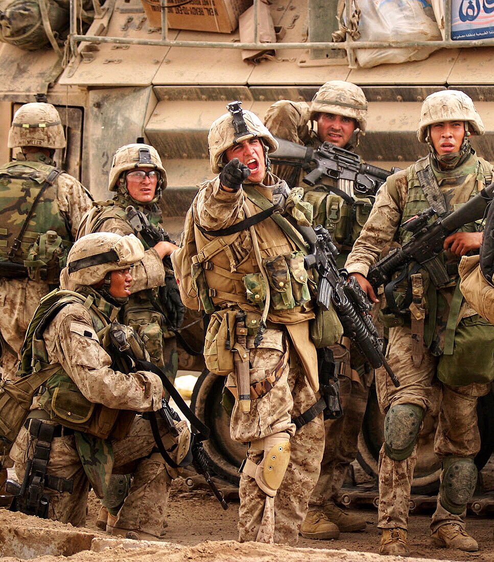 Temporarily halting his squad behind the relative shelter of an AAV, Cpl. Anthony Cucchiara of Kilo Company, 3/1, demands to know the situation of his platoon mates across the street on Friday, Nov 12, 2004. Photo by: Lucian Read. #USMC #Military #History #fallujah #oif