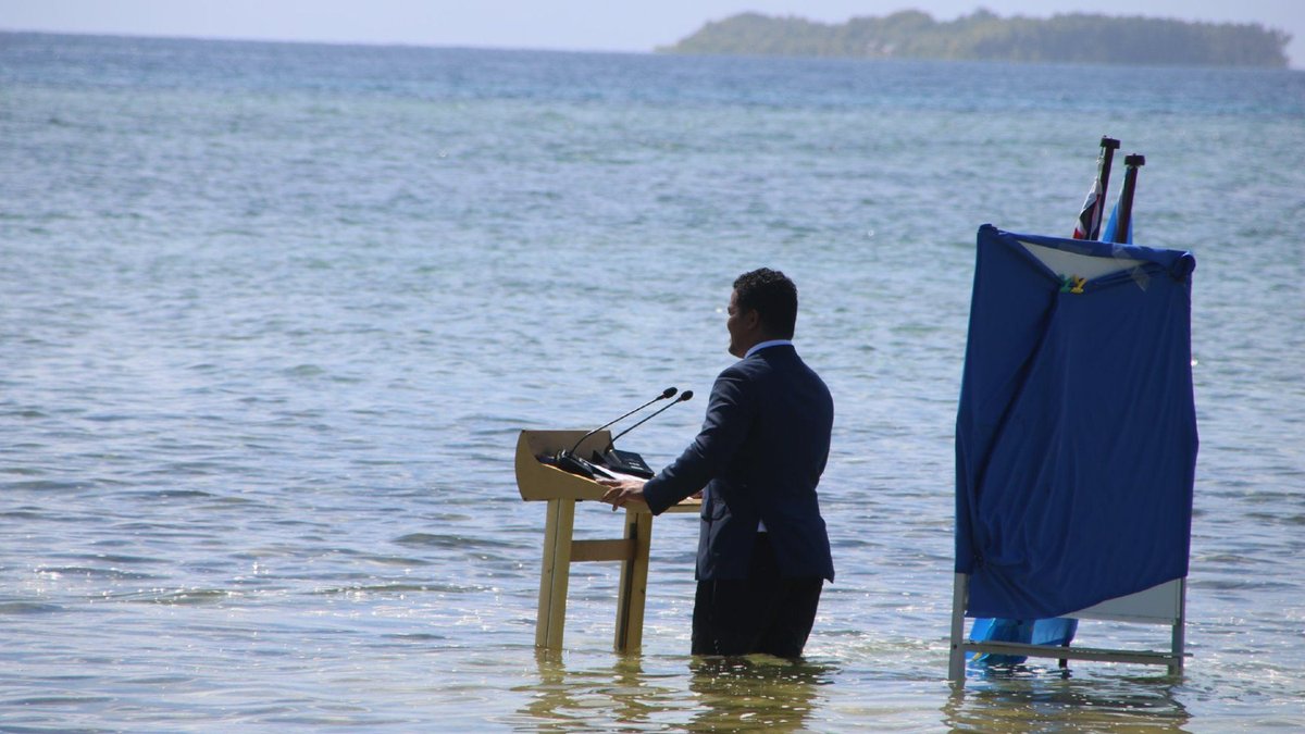 Tuvalu Foreign Minister Simon Kofe delivers a virtual speech at COP26 standing knee-deep in sea water to demonstrate the realities of climate change and rising sea levels.
