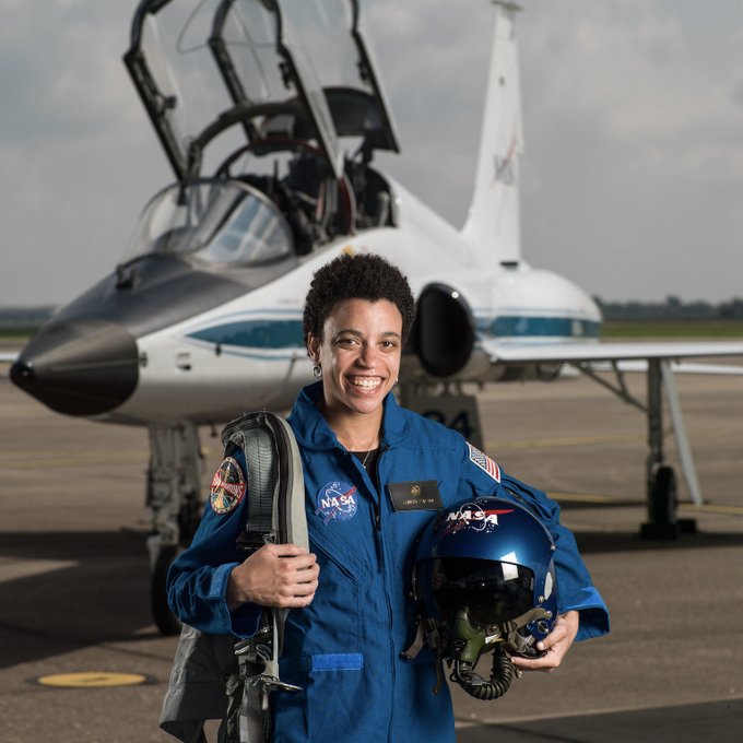 Portrait of Jessica Watkins in blue flight suit on tarmac in front of training aircraft