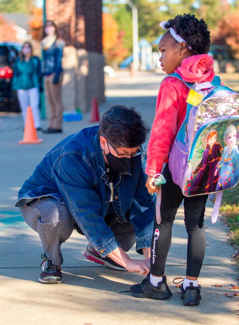 Chrys Browne, a Wake County Public Schools central office worker, helps tie a student’s shoe while working the morning carpool at <a href="/AversboroElem/">Aversboro Elementary School</a>. Wake County is having central office staff volunteer at schools to help them deal w/ staffing shortages. #wcpss #nced