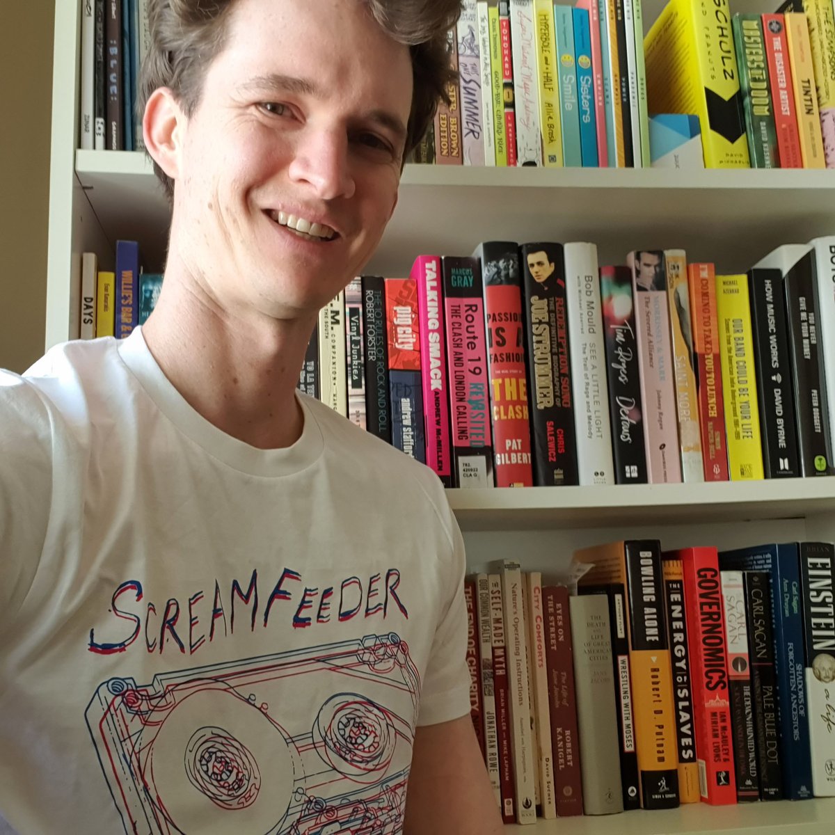 stuart_mcmillen's tweet photo. Wearing my Screamfeeder cassette T-shirt for Aus Music T-Shirt day! Photographed in front of the 'music section of my bookshelf. #AusmusicTShirtDay #AusmusicTShirtDay2021 #screamfeeder #ausmusic @DoubleJRadio #DoubleJ https://t.co/GHhFnvocNt