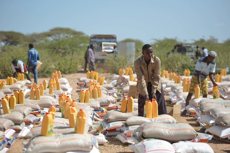Piles of bags and jerrycans. Men pick some of them up.