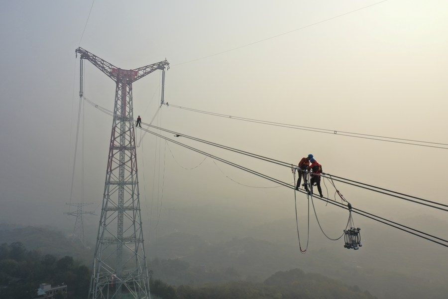PDChina's tweet photo. "Spider men" in action: Photos taken on Dec. 5, 2021 show utility technicians working on a power transmission project at a height of about 100 meters above the Yangtze River in southwest China's Chongqing. https://t.co/8D493mS1vc