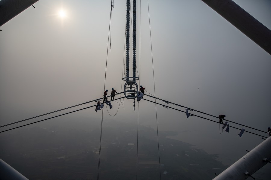 PDChina's tweet photo. "Spider men" in action: Photos taken on Dec. 5, 2021 show utility technicians working on a power transmission project at a height of about 100 meters above the Yangtze River in southwest China's Chongqing. https://t.co/8D493mS1vc