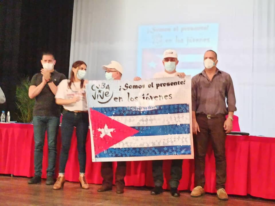 cubacooperaven's tweet photo. En nombre de los más de 11 mil colaboradores jóvenes en la Misión, se hace entrega de un pendón de la bandera cubana con las firmas de los 150 delegados del Activo Juvenil al Lic. Julio César García Rodríguez y el Lic. Juan Carlos Valdés Recio. 

#HéroesDeLaSalud #CubaVive https://t.co/OI2UUR6qUQ
