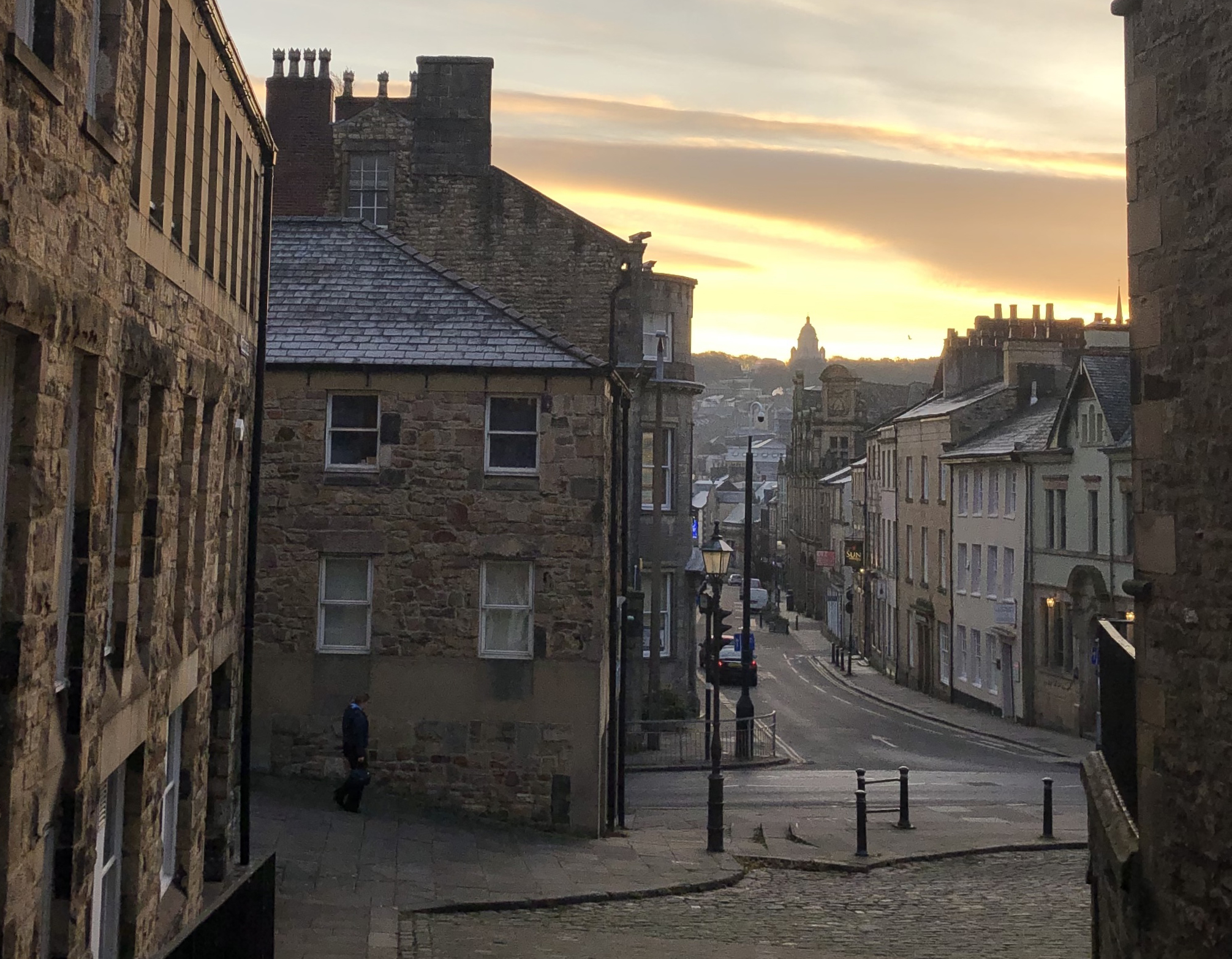 View down to Lancaster City Centre from near the Castle, with Ashton Memorial on the horizon and the sun rising behind it
