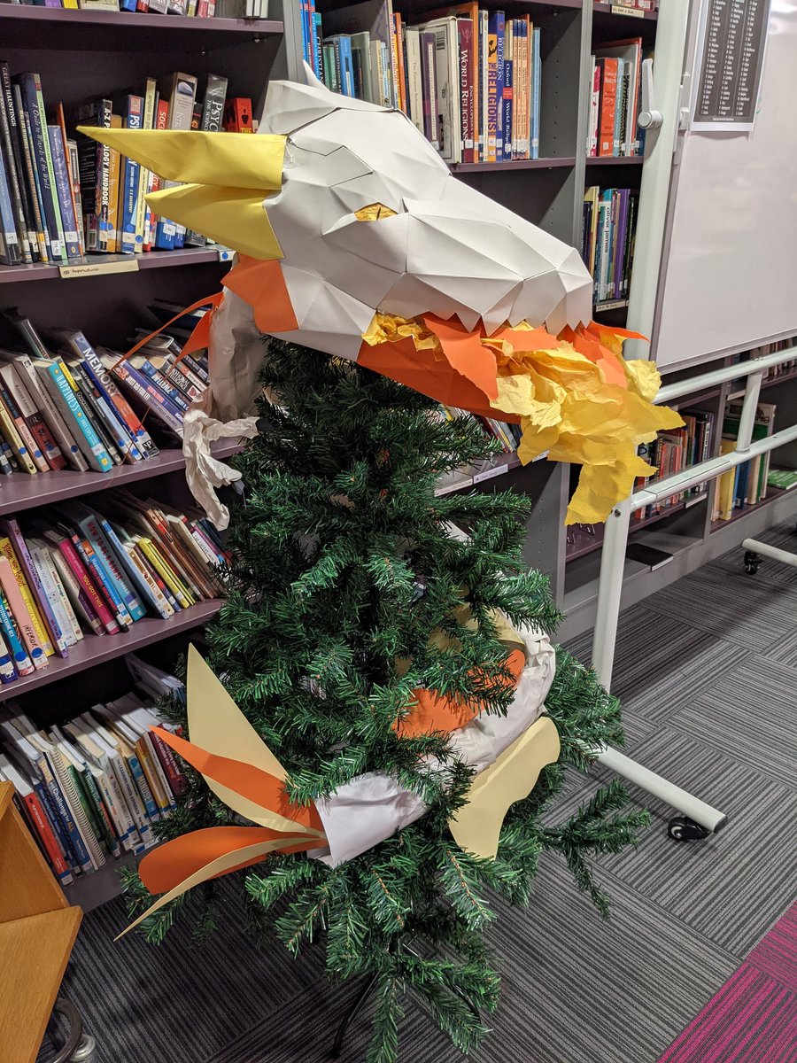 Library_EHS's tweet photo. A dragon in the library xmas tree?! Why not? I think this fierce creature needs a name. Write down your suggestions on the whiteboard and whoever's name gets picked will earn a prize! #dragon #xmastree #librarydisplay #holidaydecor https://t.co/agrIJB7vsB