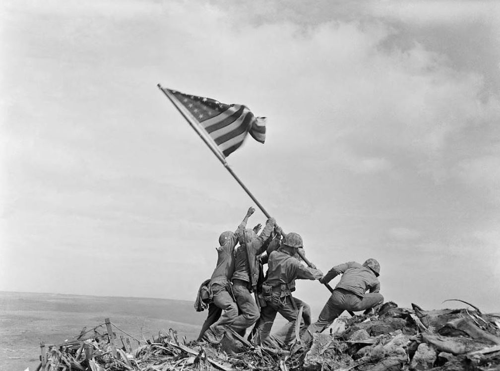 SecDefAustin's tweet photo. On Feb. 23, 1945, Marine Corps Pfc. Ira Hayes, a 22-year-old Pima Indian from Arizona, was one of the six flag raisers in the iconic World War II photo taken atop Mount Suribachi on Iwo Jima. He's on the far left side of the picture. #NativeAmericanHeritageMonth https://t.co/bNGi9HpwQd