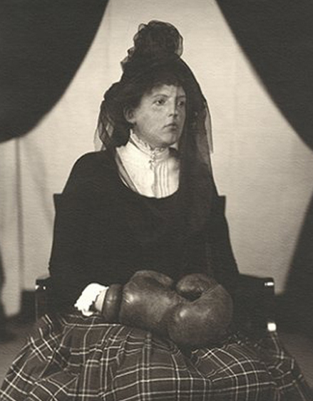 WaterPageant's tweet image. Widow of boxing legend Mickey Duggan; Lettie Duggan sat in the black corner, face covered by a widow’s veil, wearing her husband’s boxing gloves. She had eschewed Mickey’s mouthguard thinking it might detract from her grief-stricken countenance.
