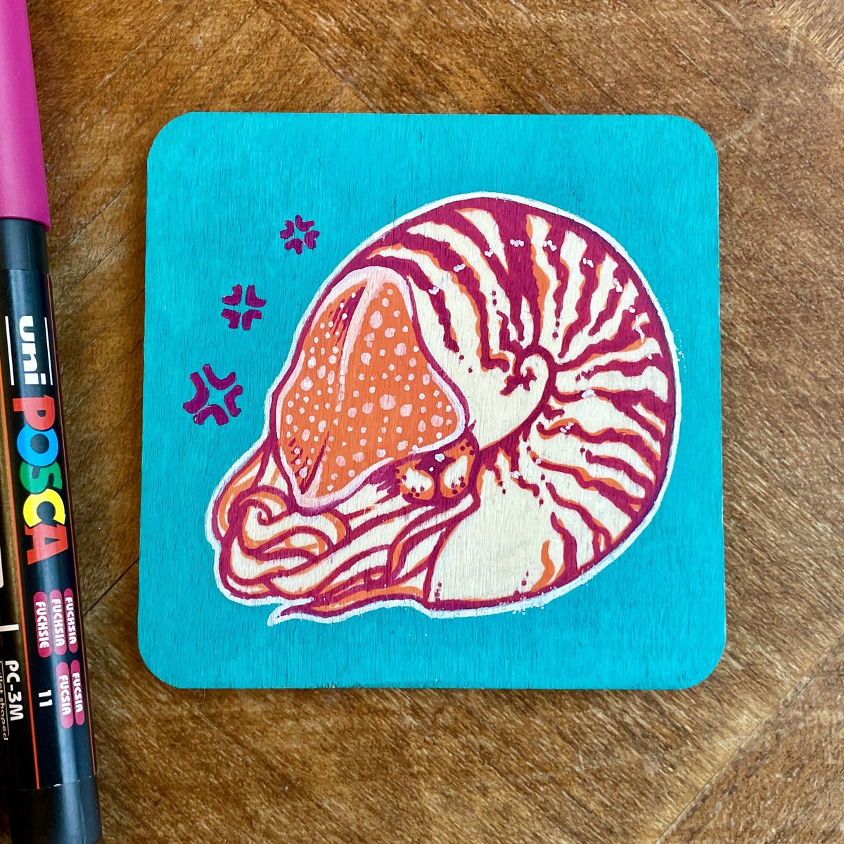 _ferntale's tweet photo. A little grumpy nautilus. Drawn with Posca paint pens on a wooden board. https://t.co/wgN8KVwlA0
