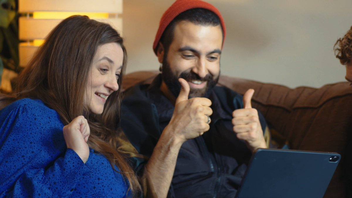 Couple sitting on a sofa using British Sign Language to communicate via Sign live app