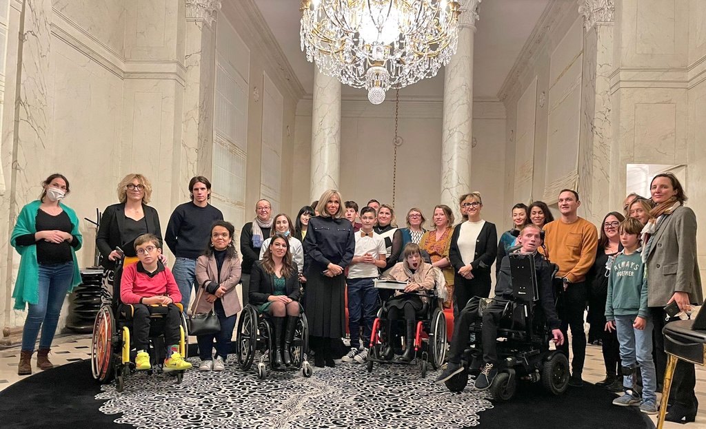 Photographie de groupe : une trentaine de personnes sont réunis pour prendre la pose dans un grand salon de l'Elysée autour de Brigitte Macron.