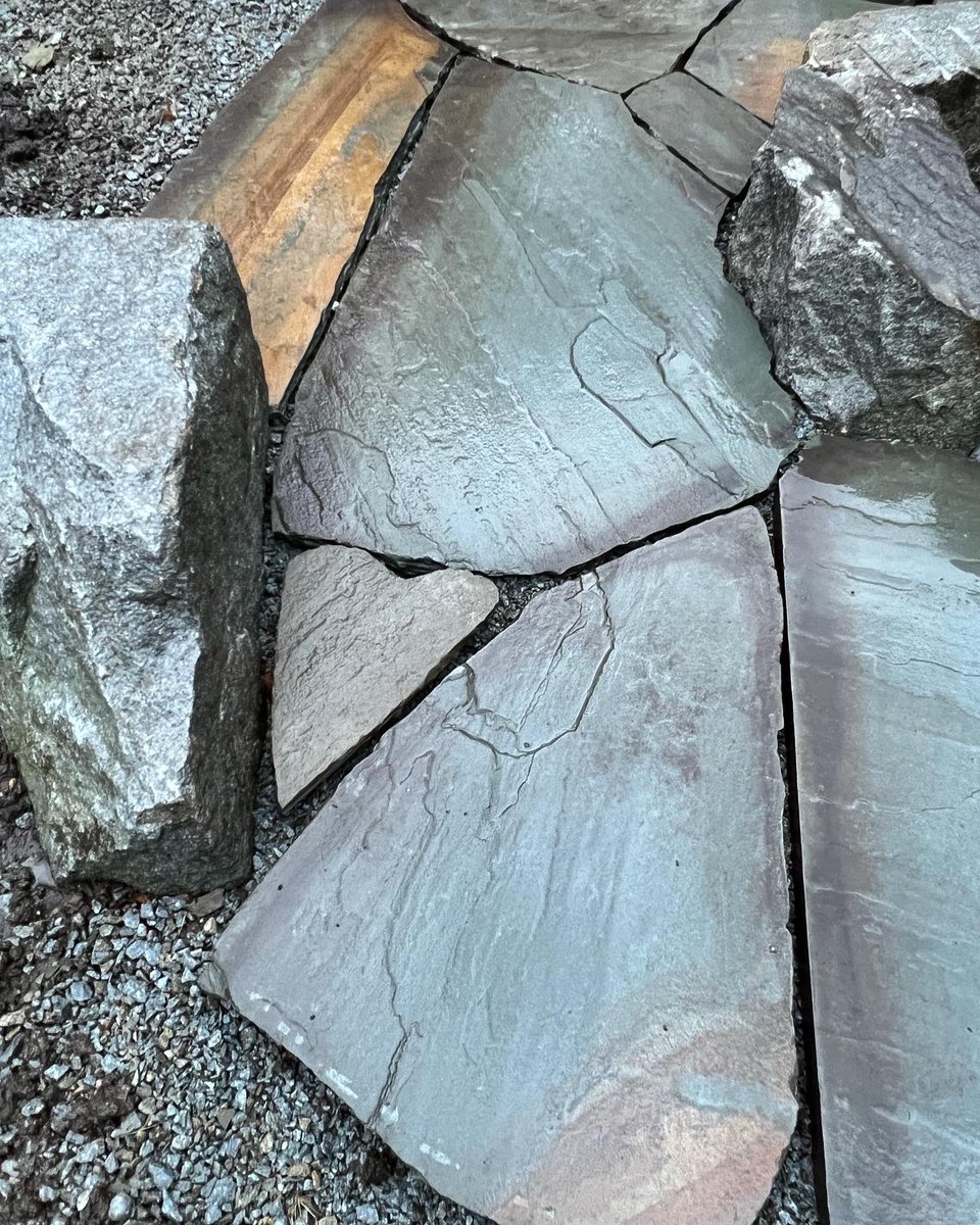 We are putting the finishing touches on this irregular bluestone fire pit area with granite boulder seats #firepits #bluestone #hardscape #graniteboulders #kandrlandscape