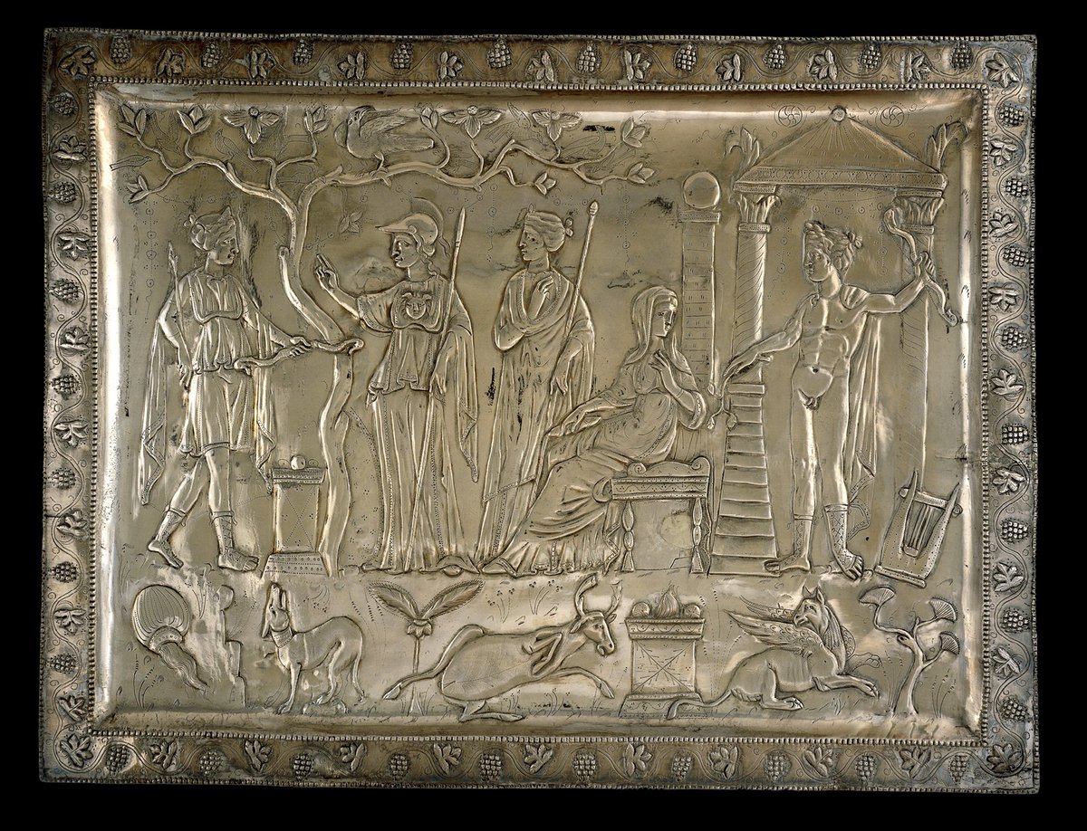 A decorative rectangular silver tray showing a scene of Roman gods, with a border of vines and grapes.