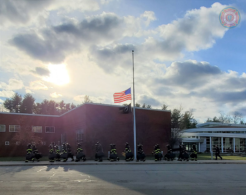 MassDFS's tweet photo. At the close of the training day on 7 Dec 2021, following Burn Day 5 activities, #Class297 marches in formation back to the classroom building. Note that the flags are at half-staff to commemorate Pearl Harbor Remembrance Day, as well as the death of Senator Robert Dole. https://t.co/rB1CtKGqYJ