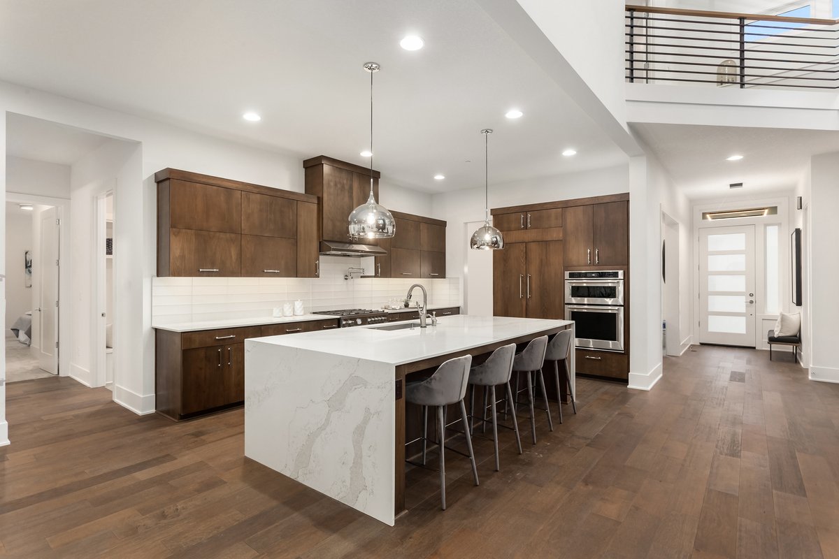 vestamarble's tweet photo. This sexy white and wood, relaxed California boho style works on so many levels. Earthy, expansive, and elegant. Rich dark matching stain  in this space ties the entirety of the design together alongside the stacked subway tile backsplash, waterfall island, and chrome pendants. https://t.co/9r2qB1uelt