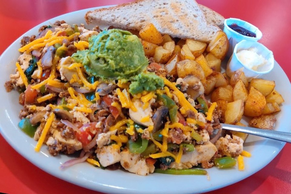 You know you’re making great choices when your meal is this colorful! Our Tofu Scramble is the whole food pyramid- 
Red and green peppers, mushrooms, onions, spinach, and plant-based cheese scrambled with tofu. Served with seasoned potatoes, avocado, wheat toast, &amp; berry jam. 🌈