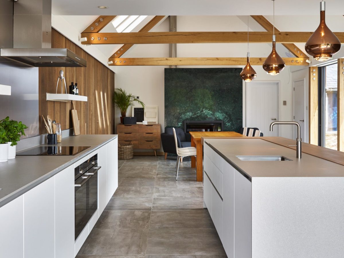 High ceilings and rustic beams meet sleek lines in this contemporary open-plan space. White and graphite cabinetry, coupled with an oak bartop and stainless-steel appliances complement this beautiful barn conversion. Inspired? See more projects here ow.ly/rxwx50H5maa