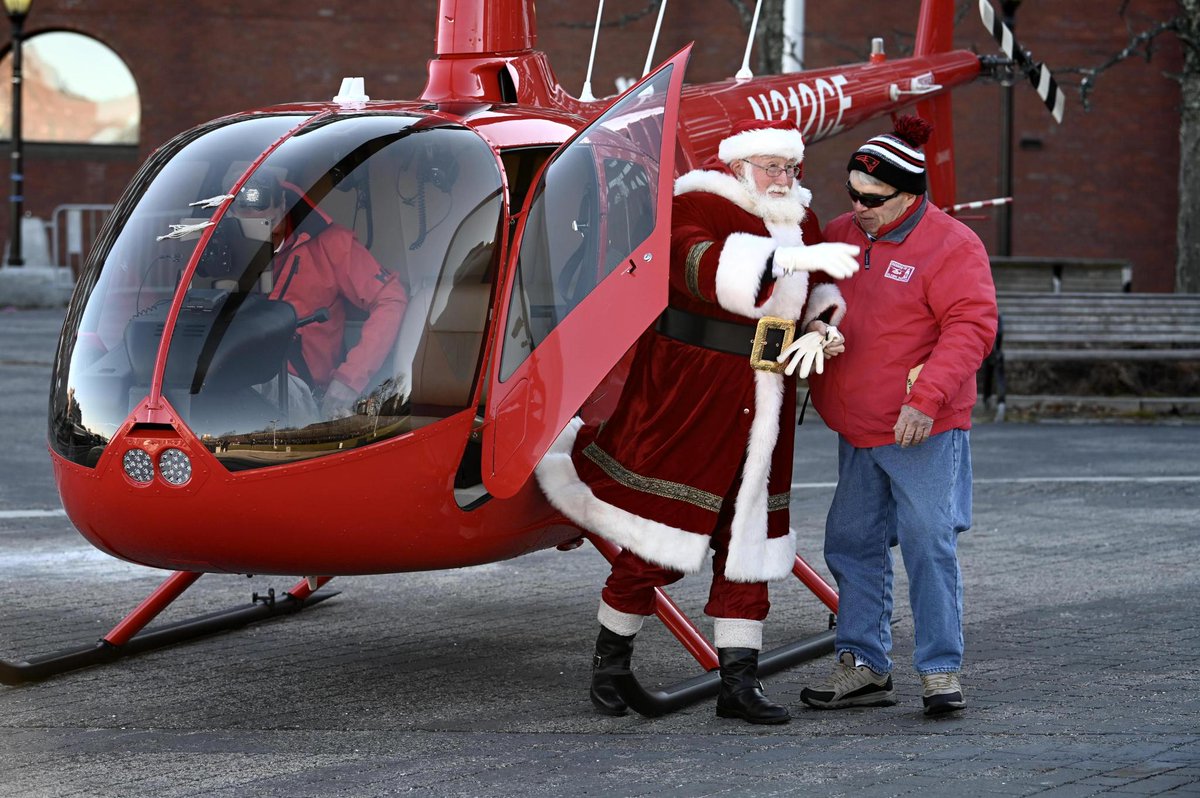 Santa exits a red helicopter.