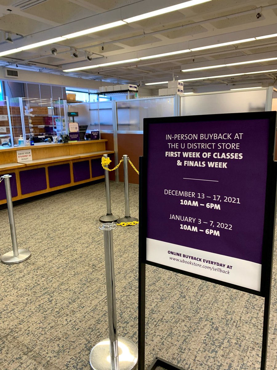 A photo of a sign in front of the Returns counter at University Book Store. The sign reads,  "In-person buyback at the U District store   first week of classes & finals week    December 13-17, 2021  10am-6pm  January 3-7, 2022  10am-6pm    Online buyback everyday at www.ubookstore.com/sellback"
